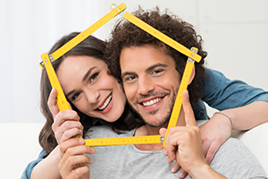 Couple holding structure of house around faces